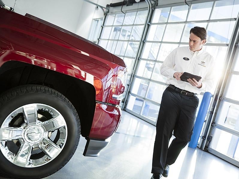 Image of service team member walking around the vehicle noting down the tire status