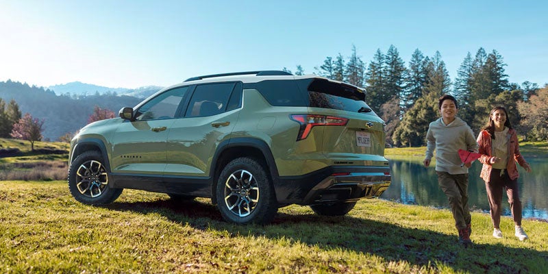 Image of kids running behind the Green color Chevrolet Equinox 2025 parked beside a pond
