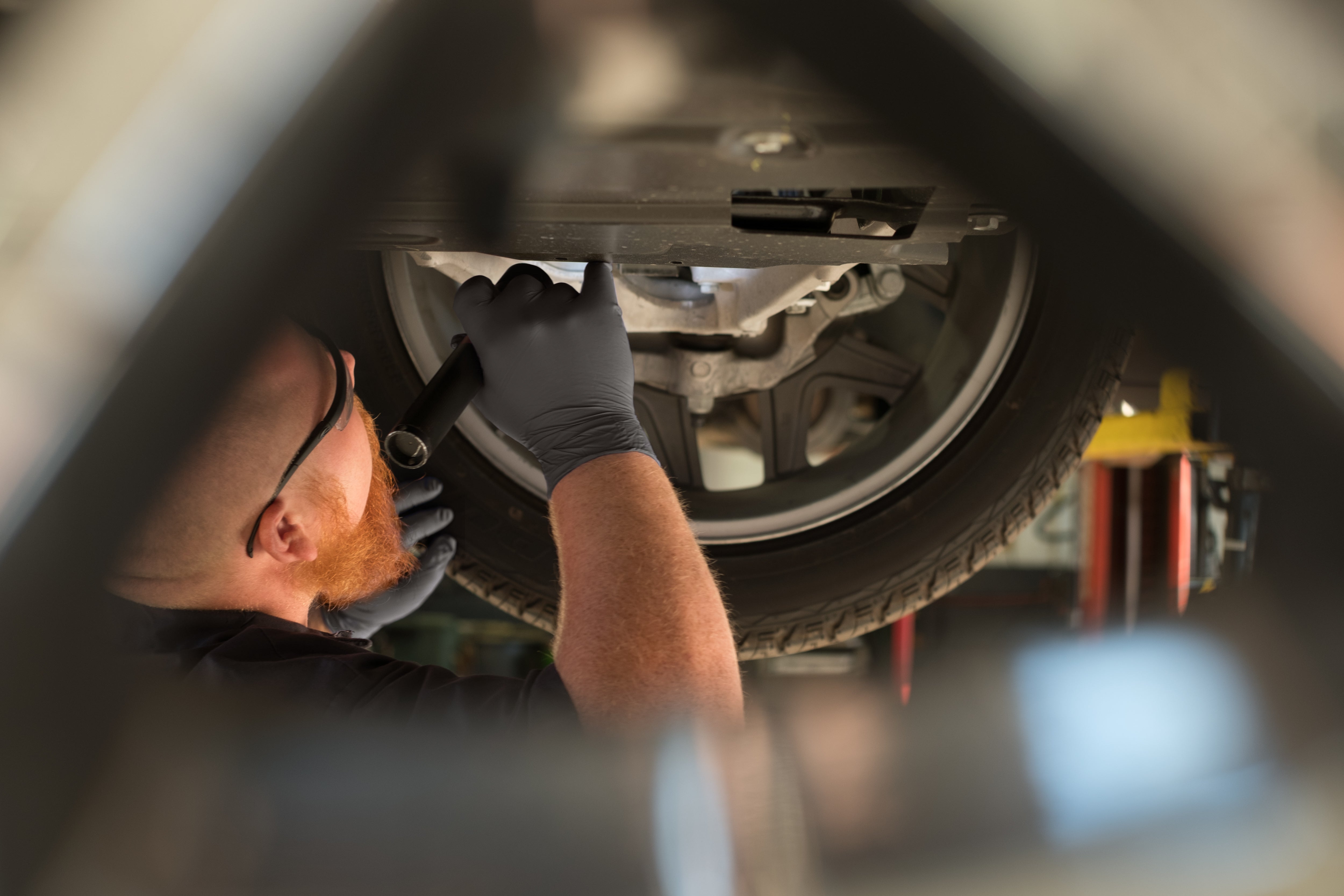 Image of service technician checking vehicle's brakes underneath the vehicle