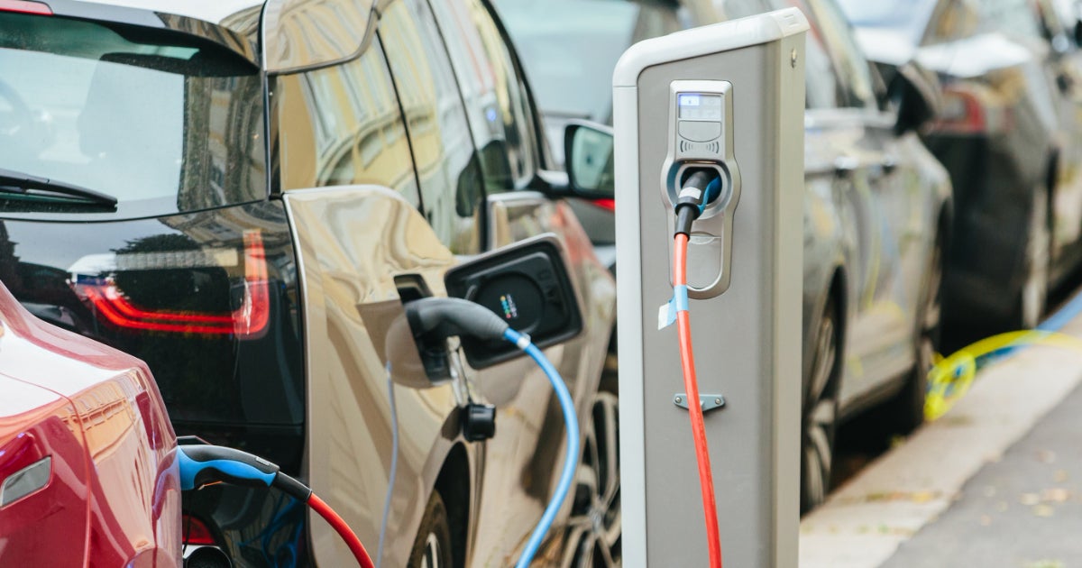 Image of vehicles parked back-to-back on the corner of the road and plugged-in to the charging station.